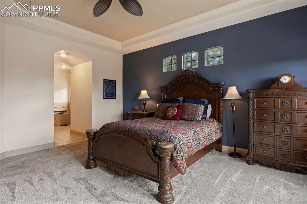 Image 17 of 50: Tiled bedroom featuring carpet floors, arched walkways, ceiling fan, a tray