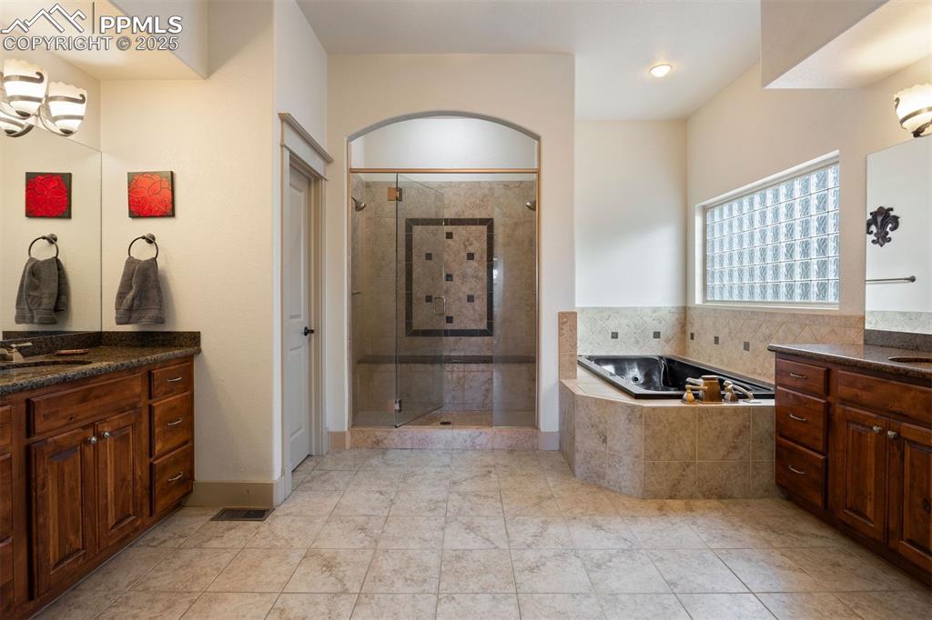 Image 19 of 50: Full bathroom with two vanities, a bath, a shower stall, and light tile pat