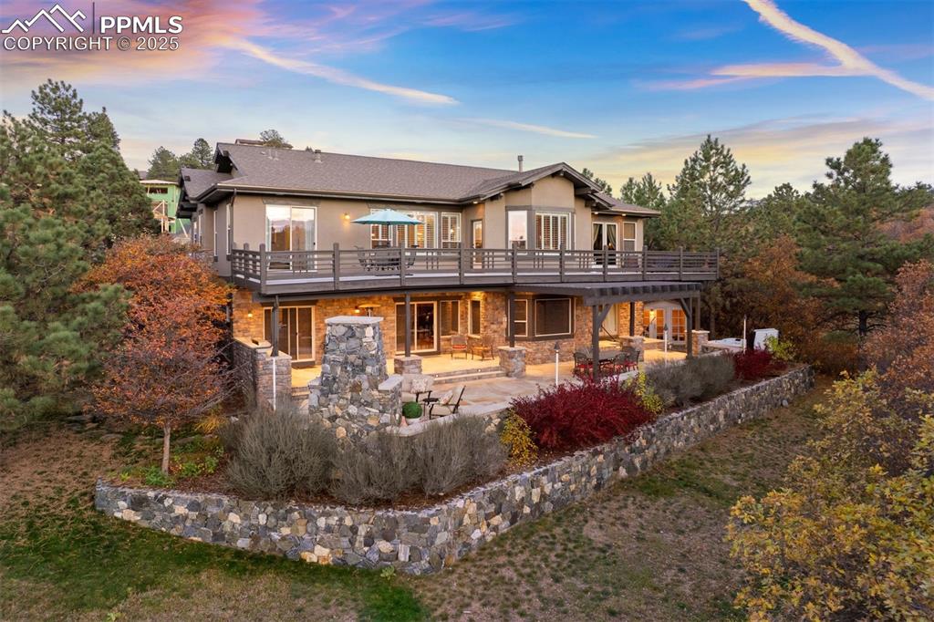 Image 2 of 50: Back of property featuring stone siding, a patio area, stucco siding, and a