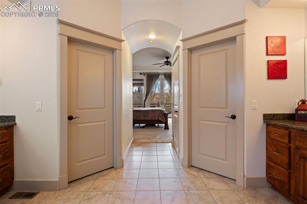 Image 20 of 50: Ensuite bathroom with vanity, ceiling fan, light tile patterned floors, and