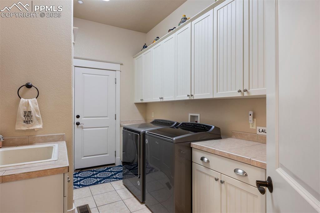 Image 24 of 50: Laundry area with light tile patterned flooring, washing machine and dryer,
