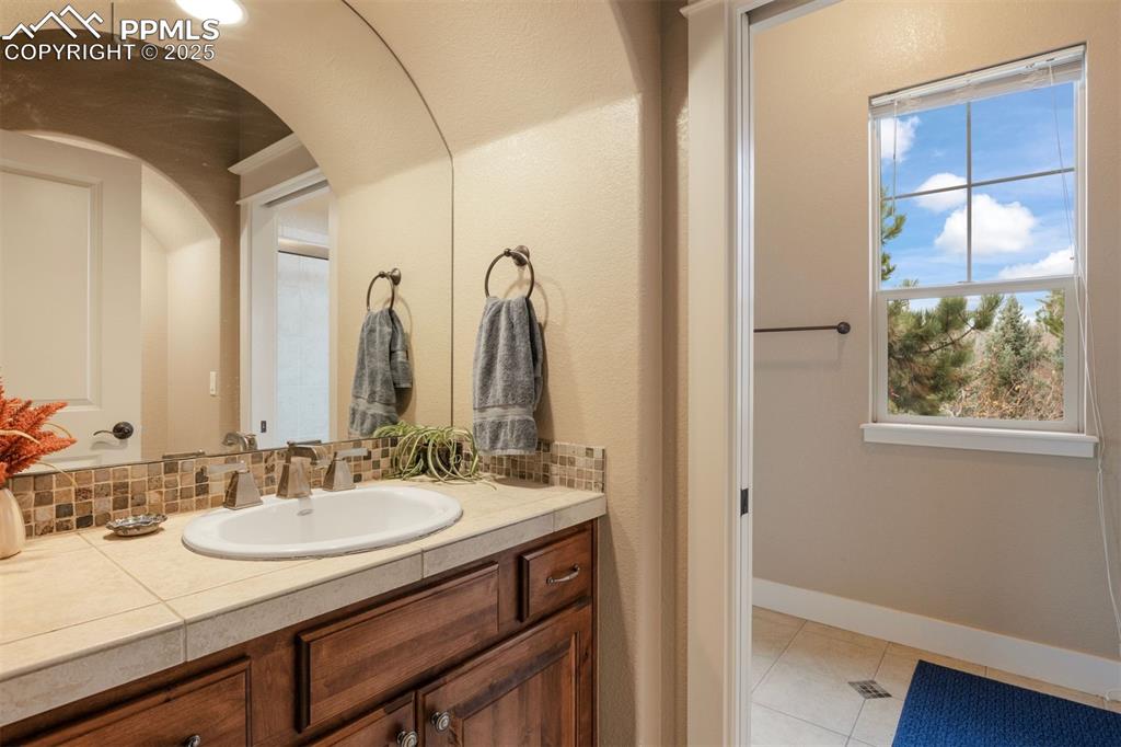 Image 26 of 50: Bathroom with vanity, light tile patterned floors, and tasteful backsplash
