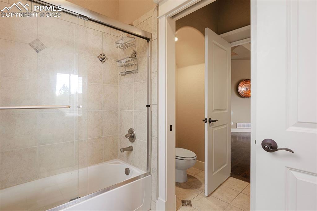 Image 27 of 50: Full bath with bath / shower combo with glass door and tile patterned floor