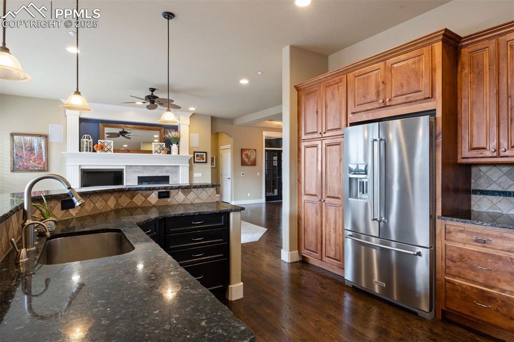 Image 8 of 50: Kitchen with tasteful backsplash, dark stone countertops, high end refriger