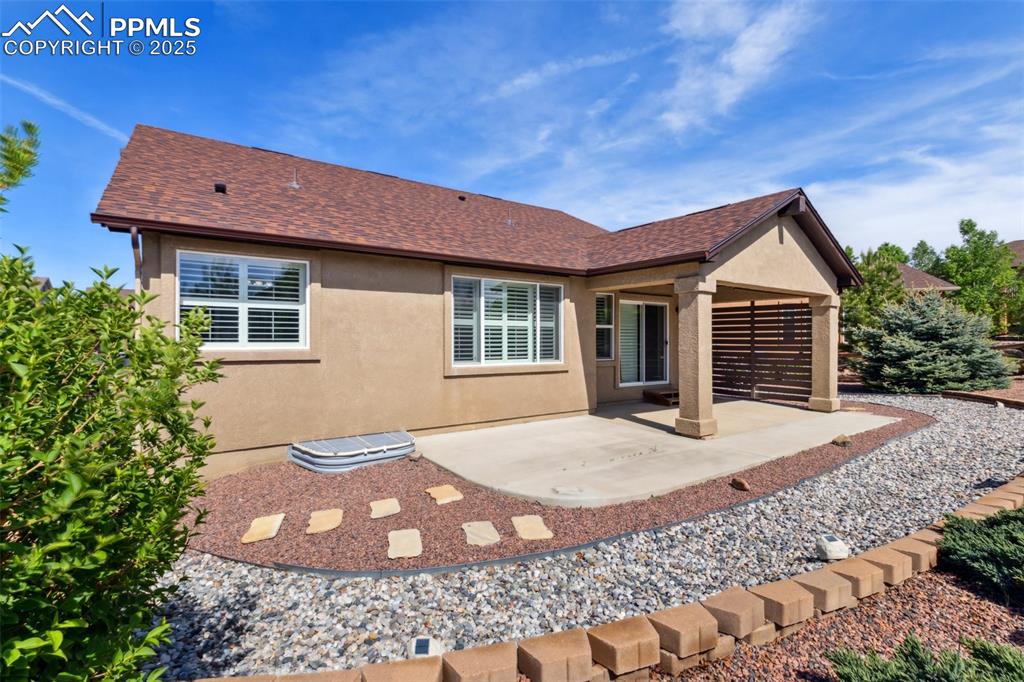 Image 11 of 50: Back of property featuring stucco siding, a patio area, and roof with class