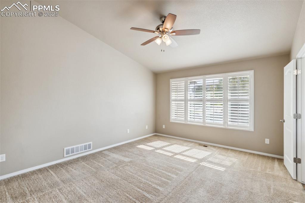 Image 13 of 50: Bedroom with a ceiling fan, light colored carpet, vaulted ceiling, and natu