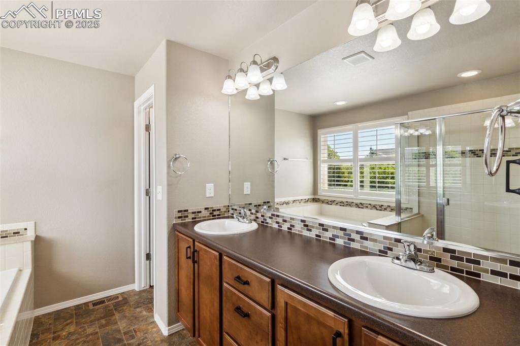 Image 15 of 50: Full bathroom with double vanity, tasteful backsplash, a garden tub, and a 