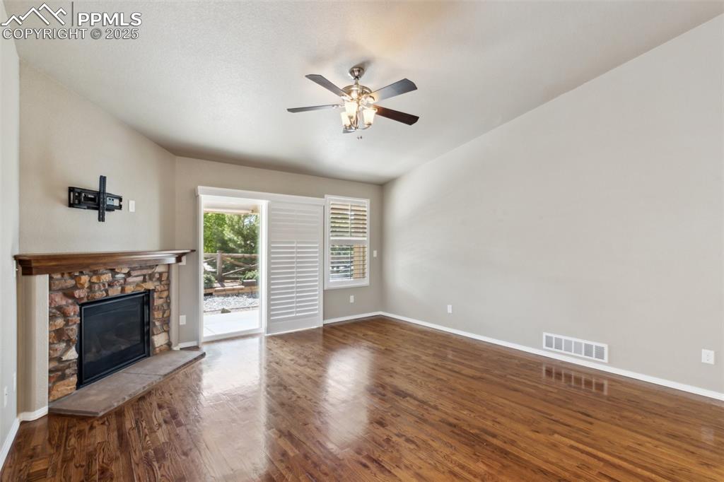 Image 22 of 50: Unfurnished living room with a fireplace, baseboards, and ceiling fan