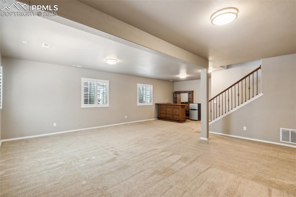 Image 26 of 50: Unfurnished basement featuring stairway, baseboards, and light colored carp
