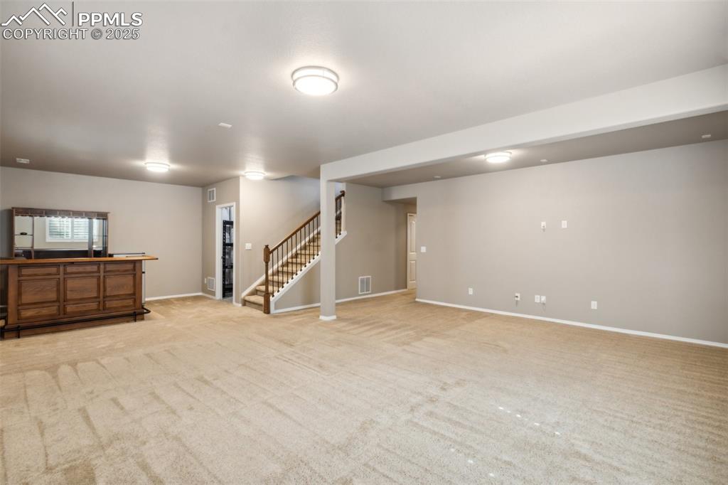 Image 27 of 50: Basement featuring stairway and light colored carpet