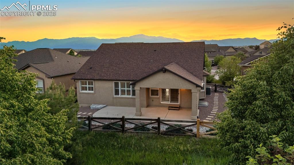 Image 3 of 50: Back of house at dusk featuring stucco siding, a patio, a mountain view, an