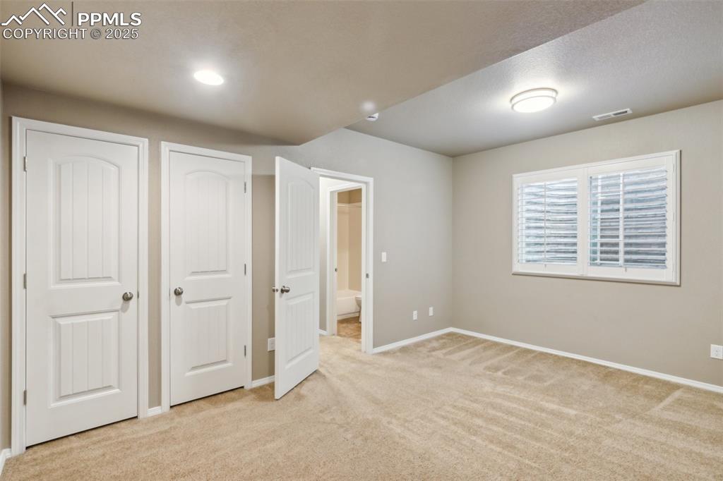 Image 36 of 50: Unfurnished bedroom with light carpet, baseboards, two-door closet