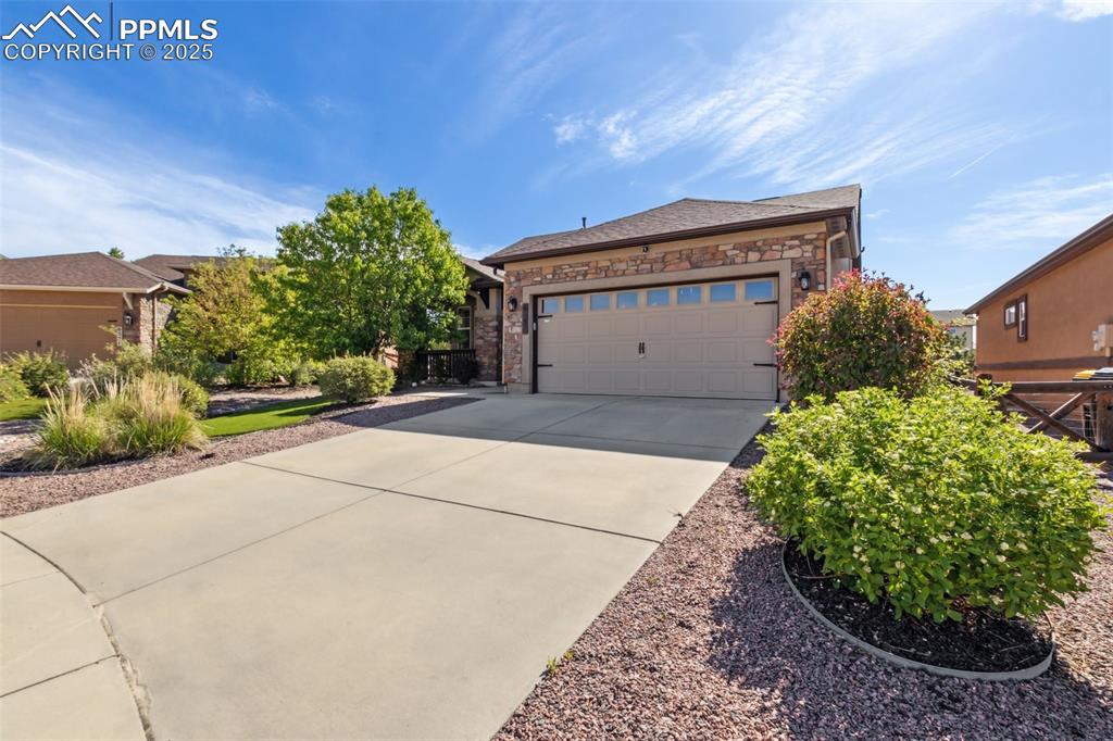 Image 37 of 50: View of front of house with driveway, stone siding, and a garage