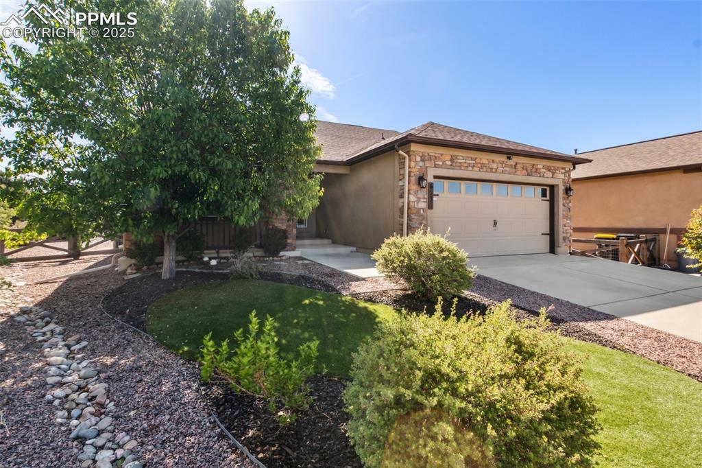 Image 38 of 50: View of front of property with an attached garage, concrete driveway, stone