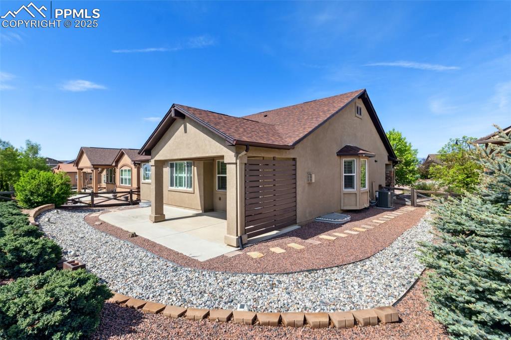 Image 40 of 50: Rear view of house with stucco siding, a patio, central AC unit, and a shin