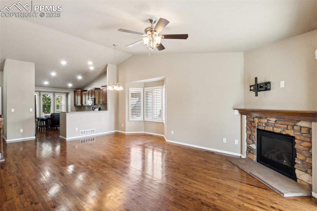 Image 8 of 50: Unfurnished living room featuring a fireplace, ceiling fan, lofted ceiling,