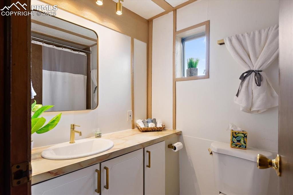 Image 17 of 50: Bathroom with curtained shower, toilet, and vanity