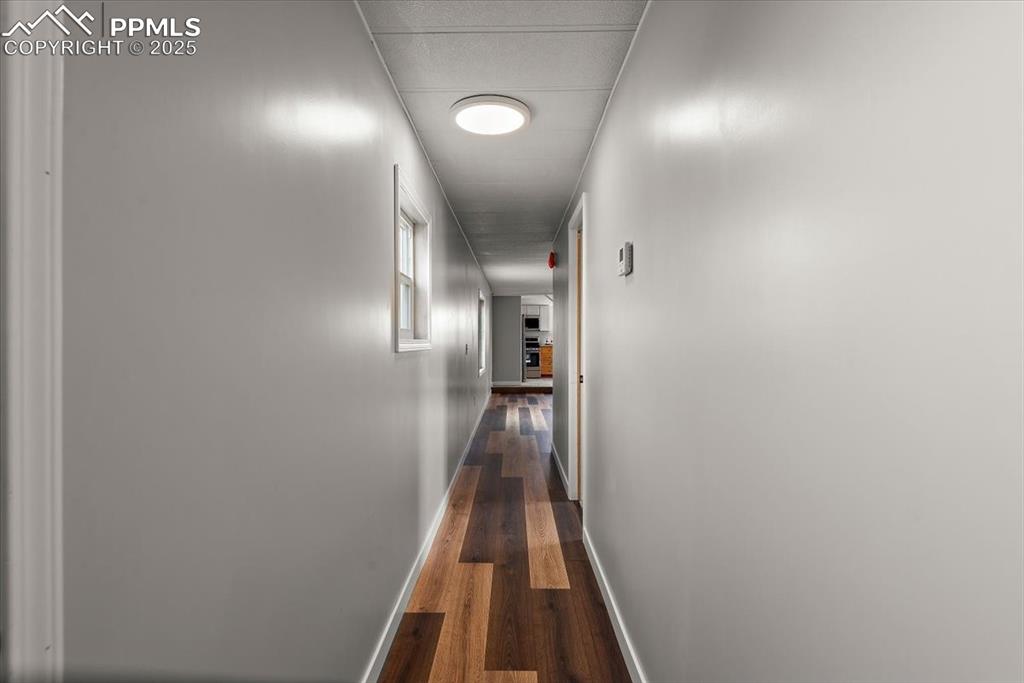 Image 28 of 50: Hall with dark wood-style floors and baseboards