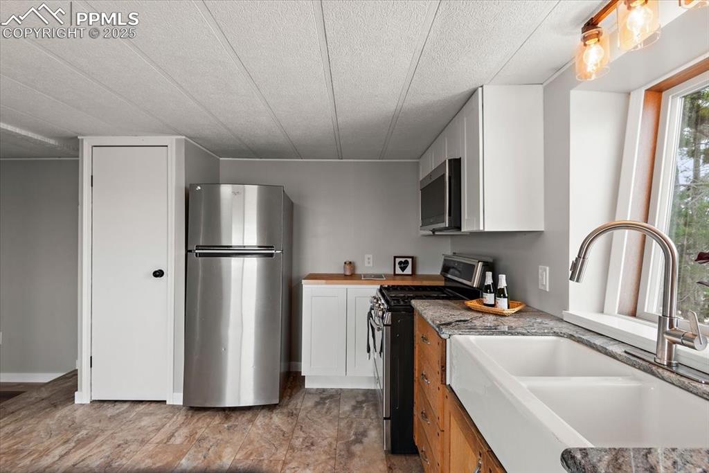 Image 32 of 50: Kitchen with a sink, white cabinets, appliances with stainless steel finish