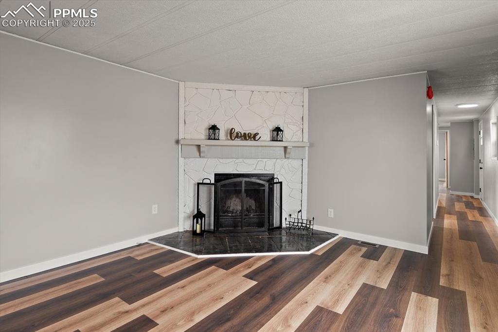 Image 33 of 50: Living room featuring baseboards, a fireplace, and wood finished floors