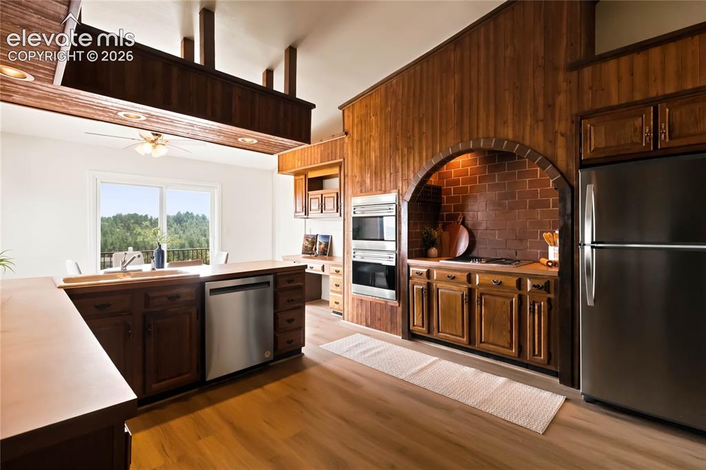 Image 12 of 49: Spacious kitchen featuring wood cabinetry, stainless steel appliances, wood