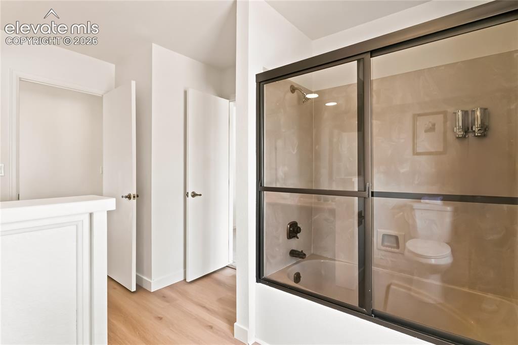 Image 16 of 49: Bathroom featuring a shower-tub combination with sliding glass doors, a wal