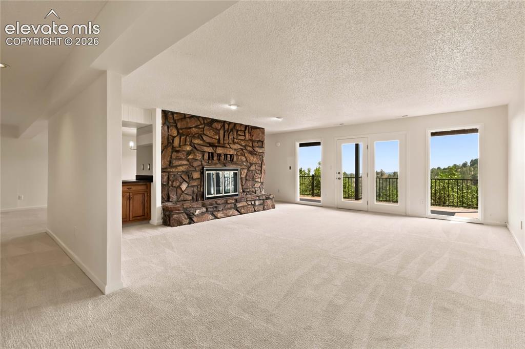 Image 26 of 49: Expansive living area featuring a stone fireplace, light-toned carpeting, a