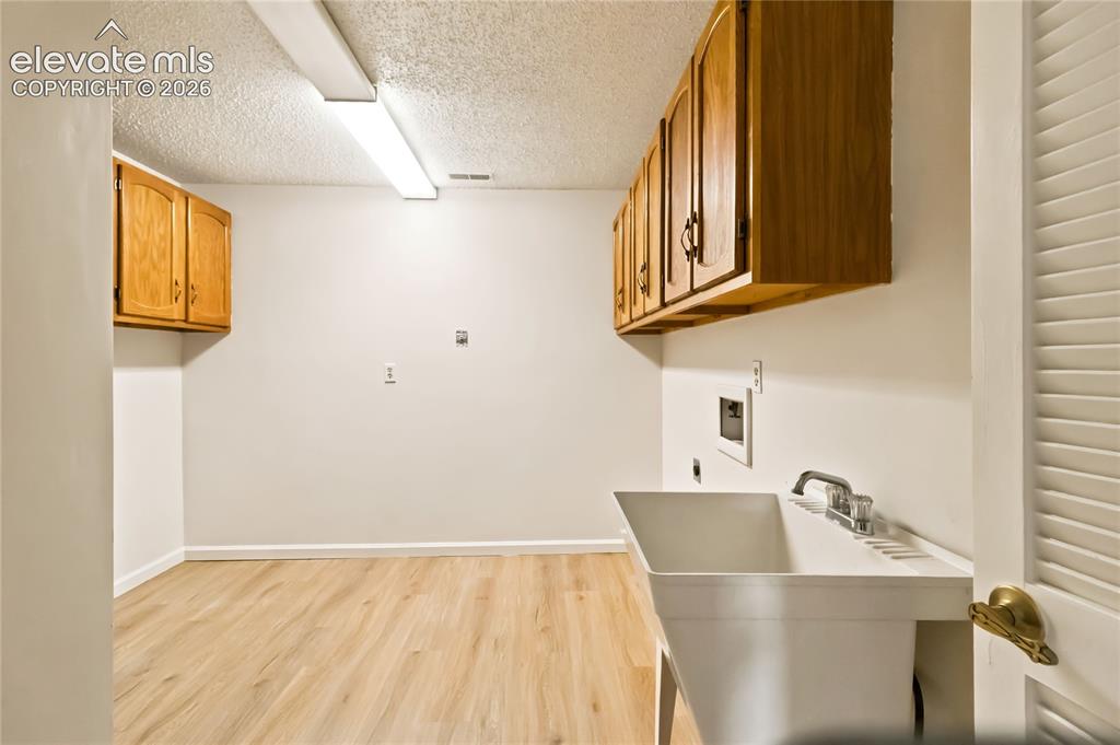 Image 30 of 49: Utility room featuring stainless steel sink with chrome faucet, wooden cabi