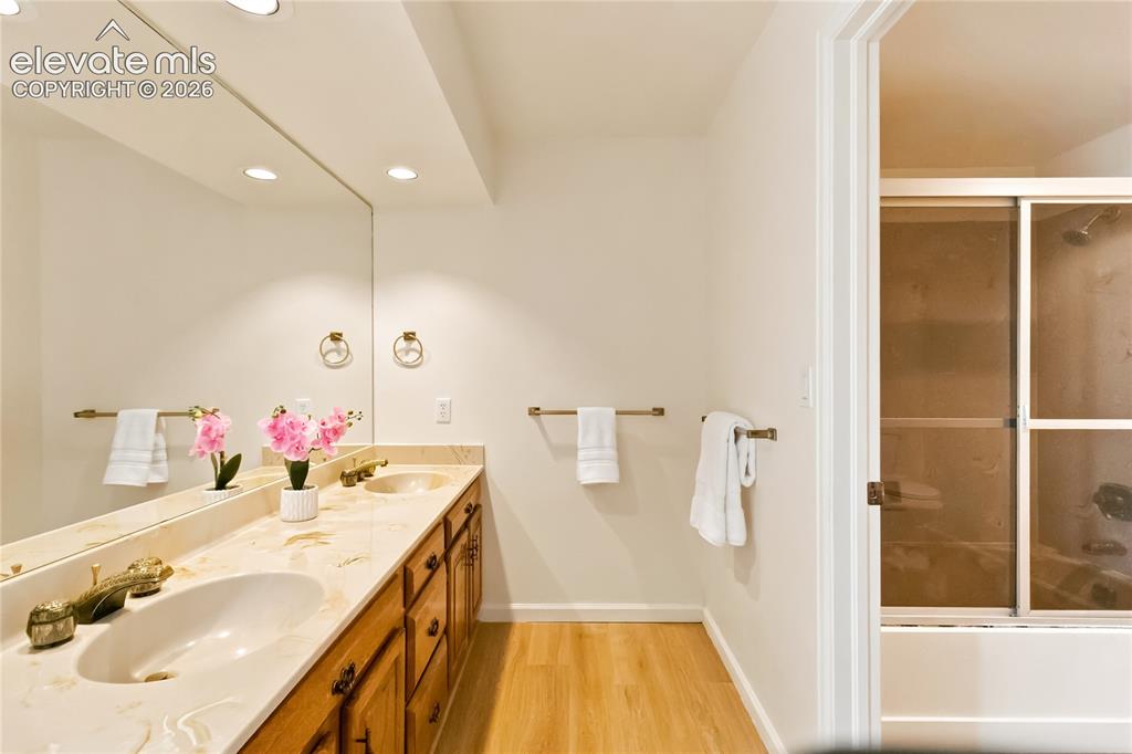 Image 34 of 49: Spa-inspired primary bathroom featuring a wood-finish vanity with dual unde