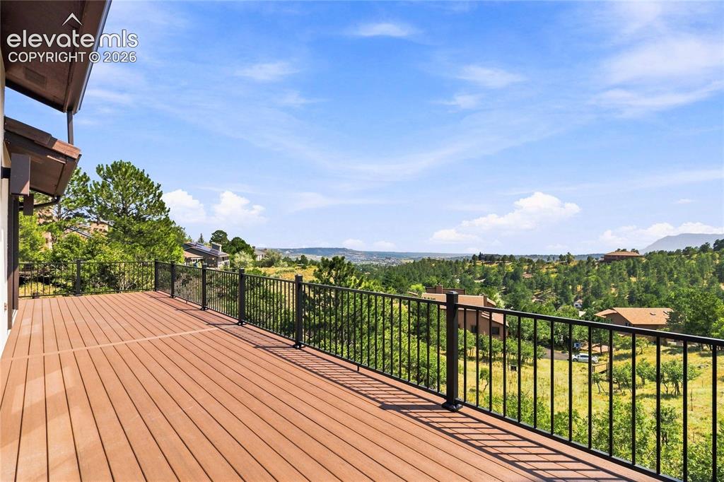 Image 37 of 49: Expansive composite wood deck with black metal railing system overlooking l