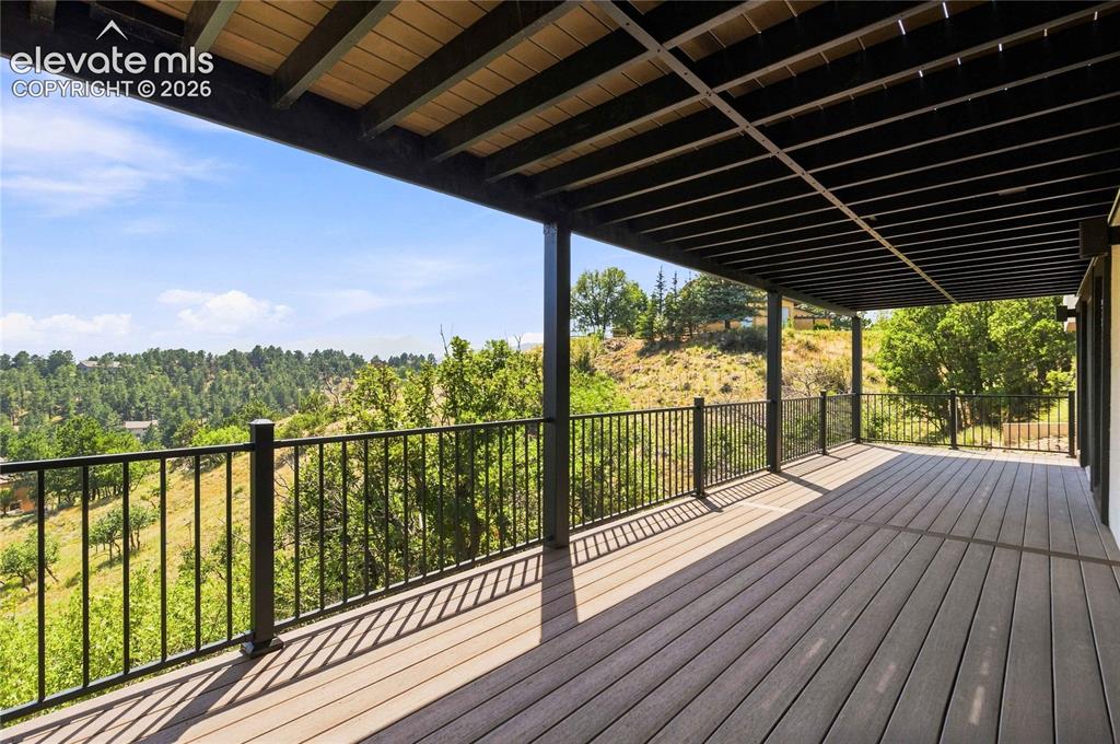 Image 39 of 49: Expansive covered deck featuring composite decking, black metal railings, a