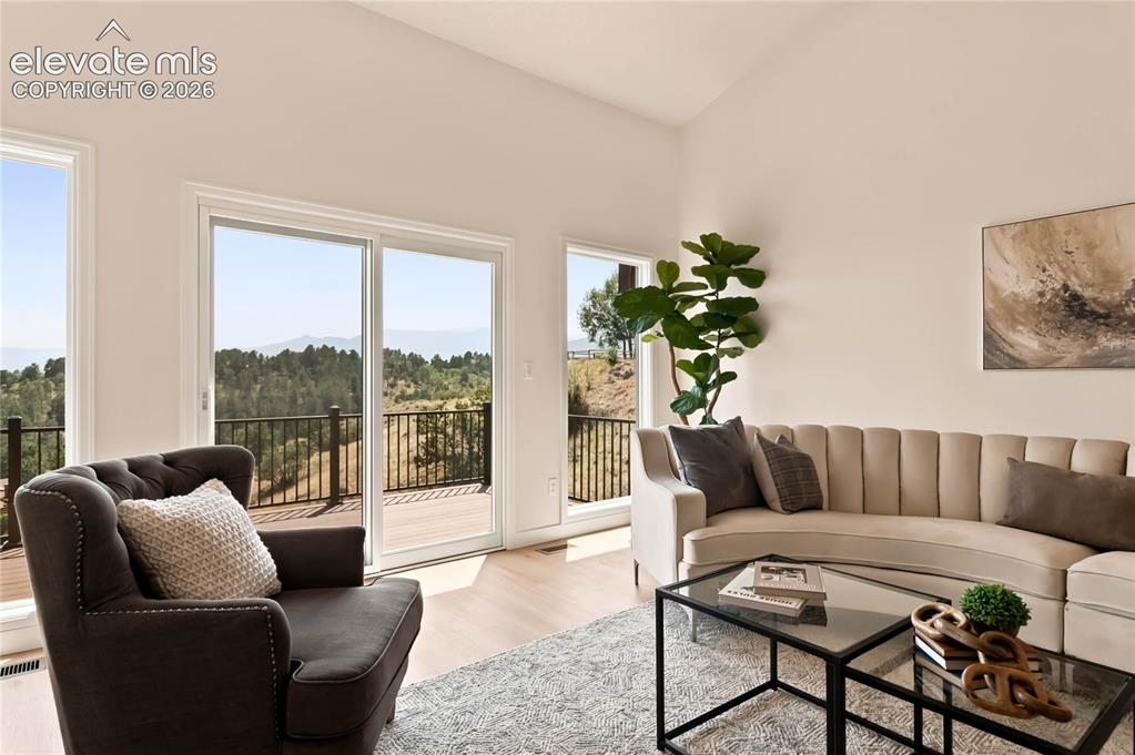 Image 5 of 49: Bright, light-filled living space featuring expansive glass doors and windo