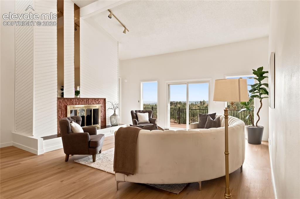 Image 6 of 49: Vaulted ceiling, wood-finish flooring, white brick fireplace surround with 