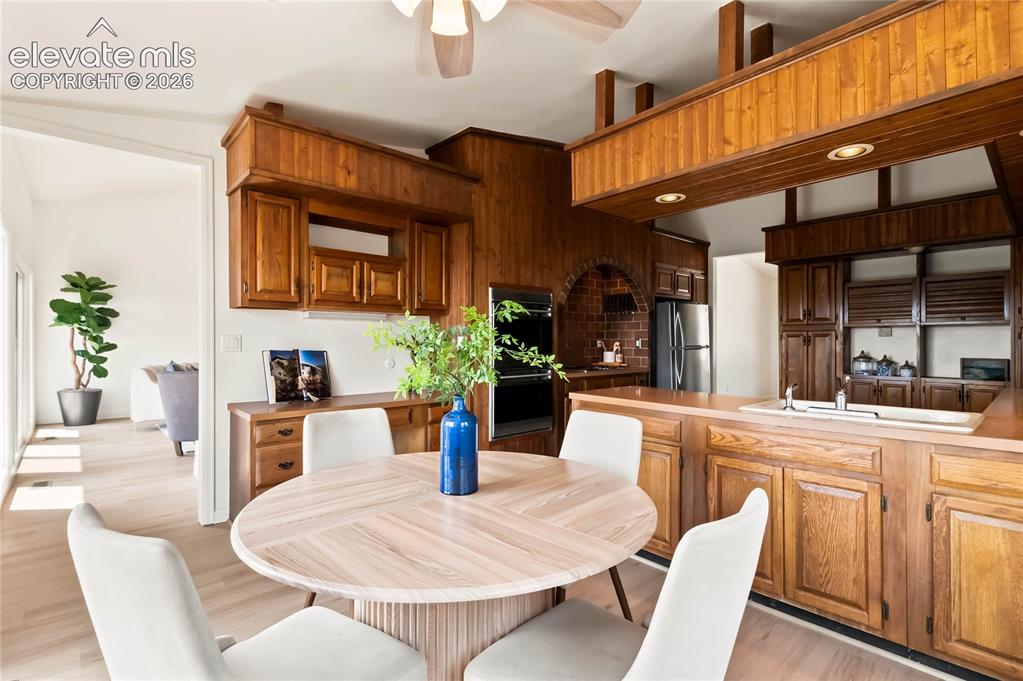 Image 8 of 49: Integrated kitchen and dining area featuring wood cabinetry, built-in ovens