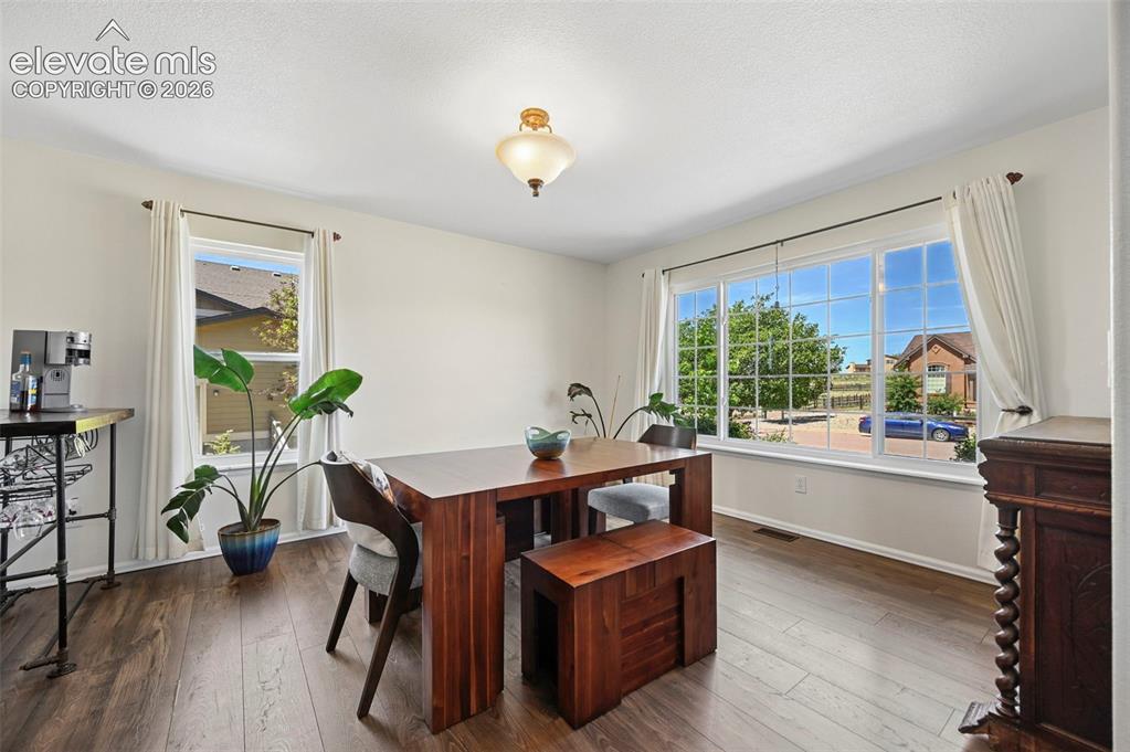 Image 11 of 36: Dining space featuring wood-finish flooring, a large multi-pane window, and