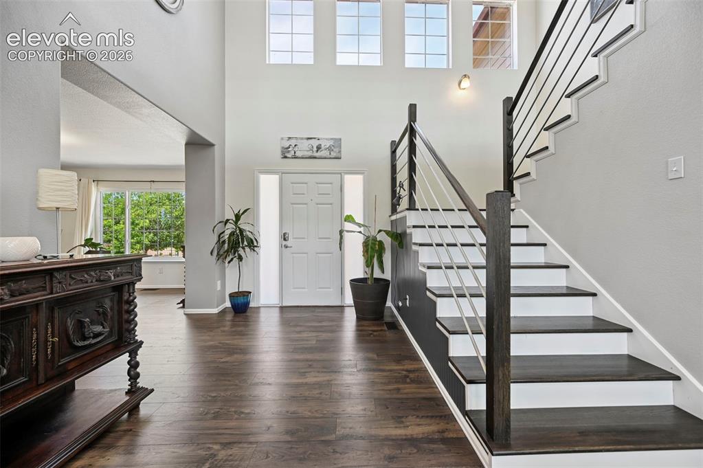 Image 12 of 36: Two-story foyer featuring dark wood-finish flooring, a modern staircase wit