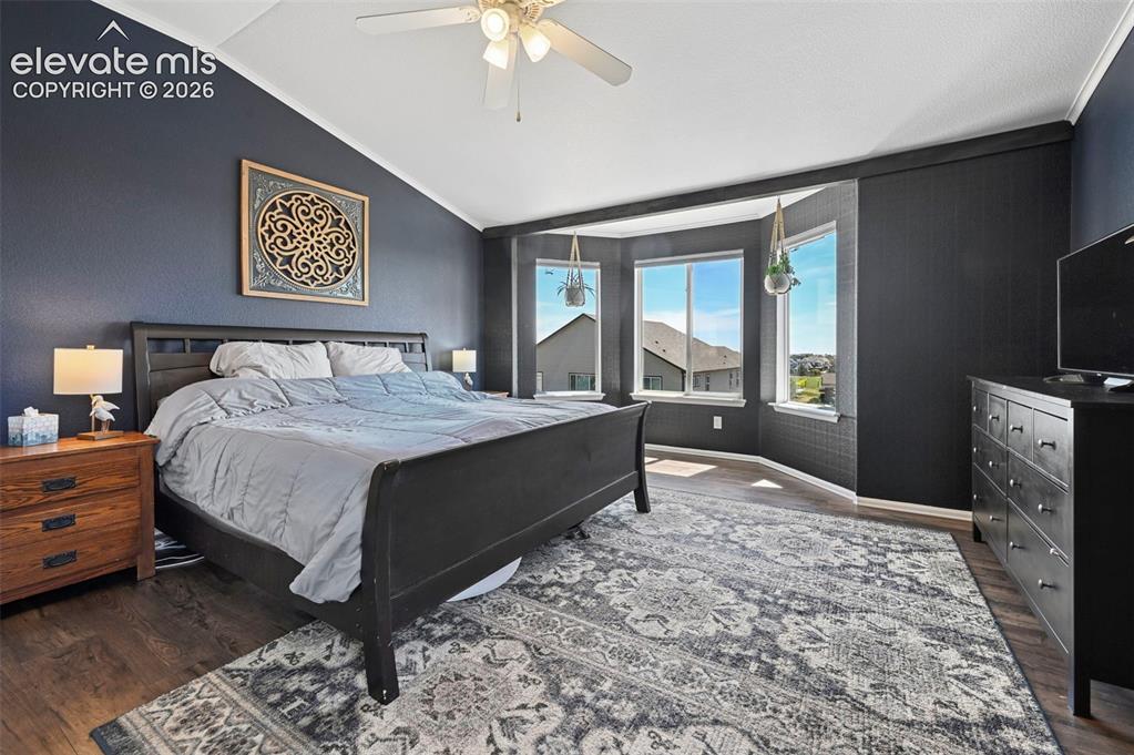 Image 13 of 36: Spacious bedroom featuring wood-finish flooring and a vaulted ceiling with 
