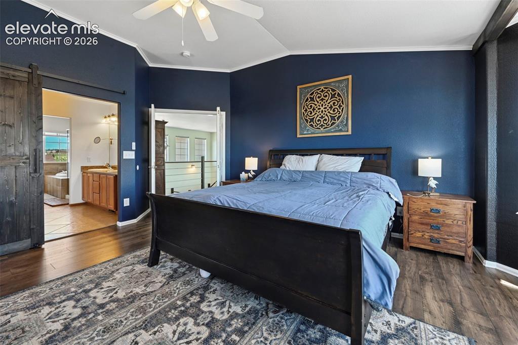 Image 16 of 36: Bedroom featuring wood-finish flooring, a ceiling fan, and a barn door entr