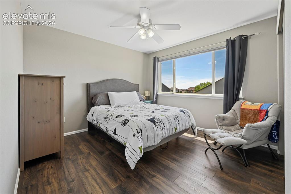 Image 17 of 36: Bedroom featuring wood-finish flooring, a wide window, ceiling fan, neutral