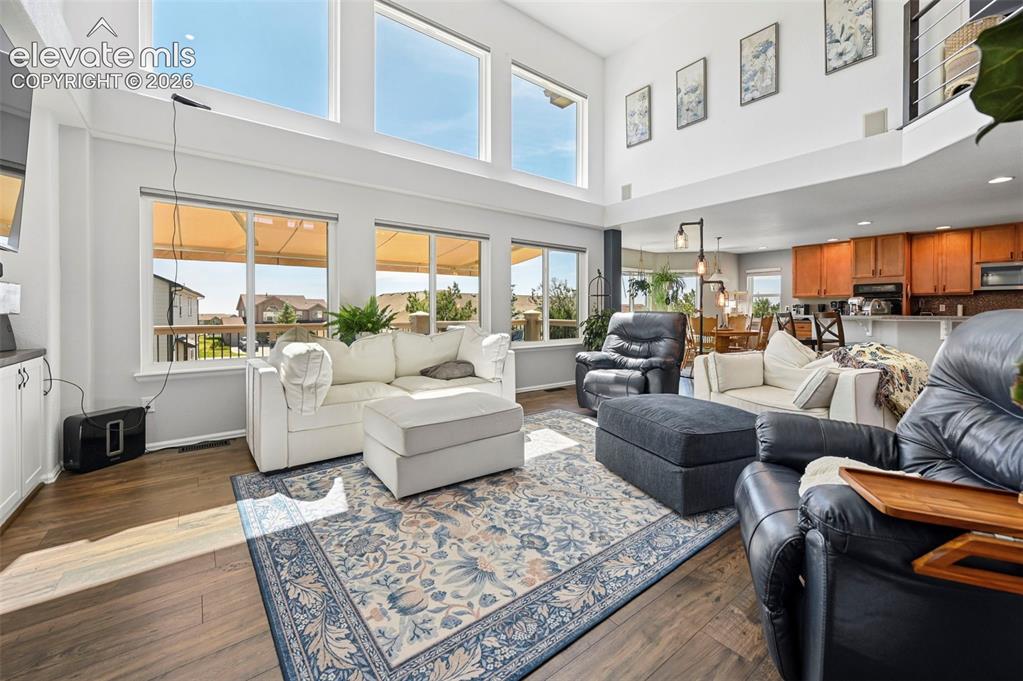 Image 2 of 36: Spacious living area featuring wood-finish flooring, high ceilings, and a w
