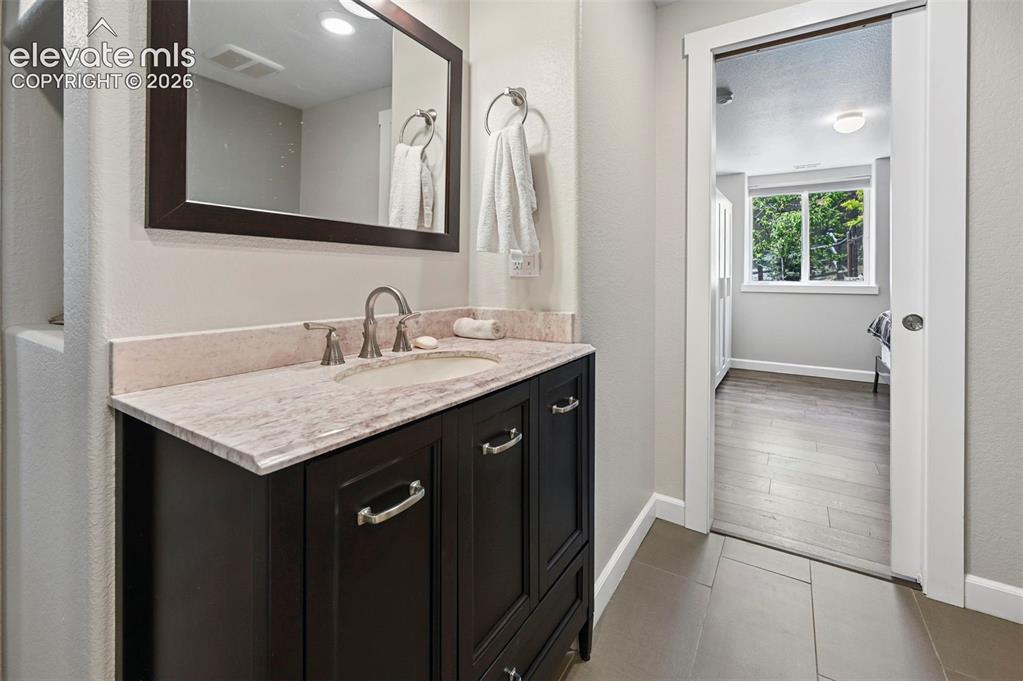 Image 24 of 36: Bathroom vanity featuring a dark wood-finish cabinet with silver hardware, 