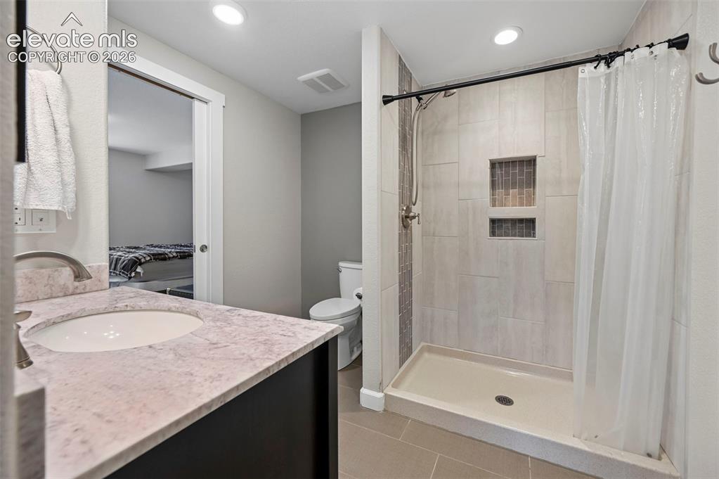 Image 25 of 36: Bathroom featuring a vanity with an undermount sink, a countertop with a st