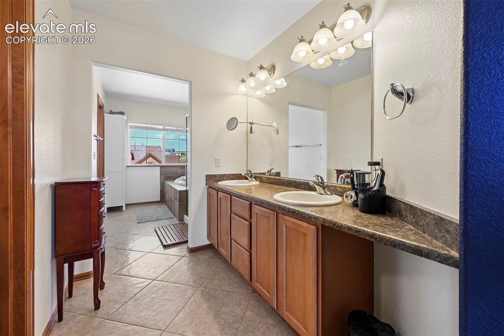 Image 26 of 36: Bathroom featuring a dual vanity with integrated sinks, a large mirror, and