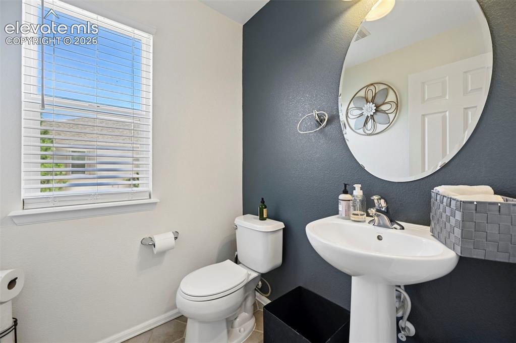Image 27 of 36: Bathroom featuring a pedestal sink, oval mirror, toilet, and a window with 