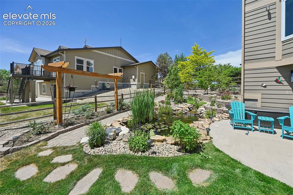 Image 34 of 36: Multi-level backyard featuring a serene pond, natural rock landscaping, mat