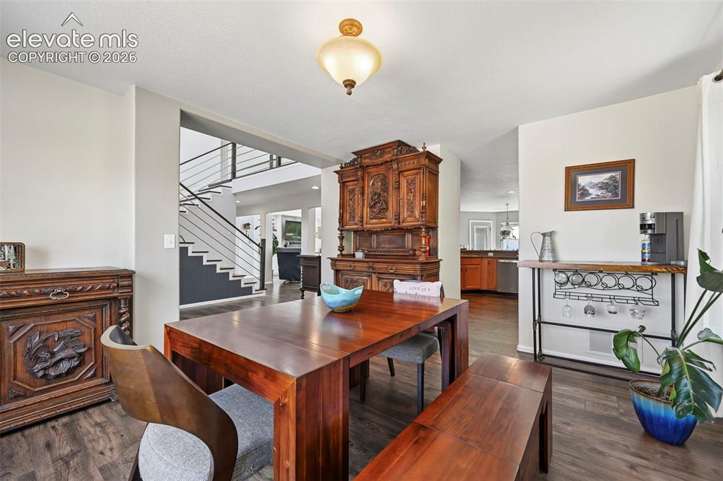 Image 4 of 36: Spacious dining area featuring wood-finish flooring, a contemporary overhea