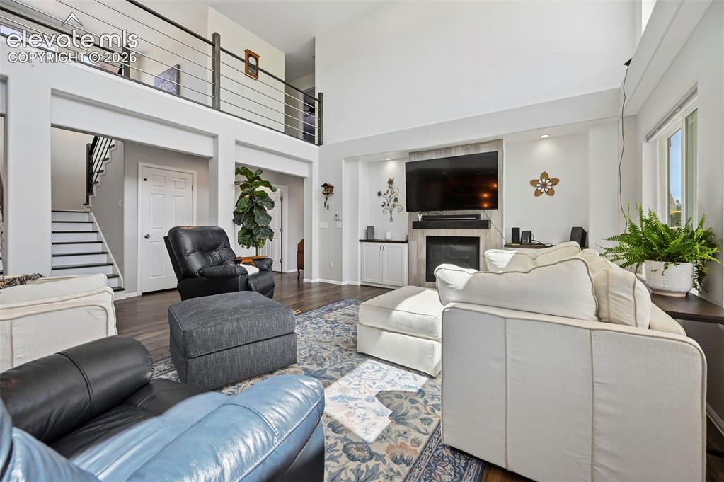 Image 6 of 36: Spacious living area featuring a vaulted ceiling, wood-finish flooring, and