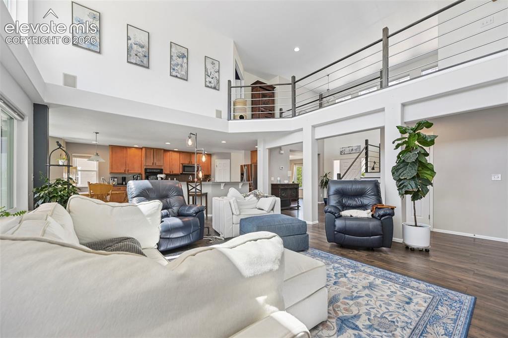 Image 9 of 36: Expansive living area featuring vaulted ceilings, wood-finish flooring, and