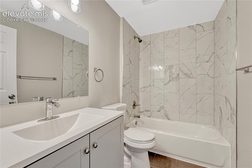 Image 23 of 41: Integrated bathtub with tiled surround, light-toned vanity with undermount