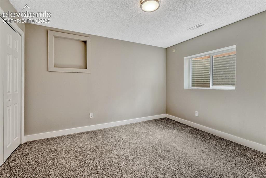 Image 25 of 41: Neutral tone wall paint, textured ceiling, flush mount ceiling light, priva